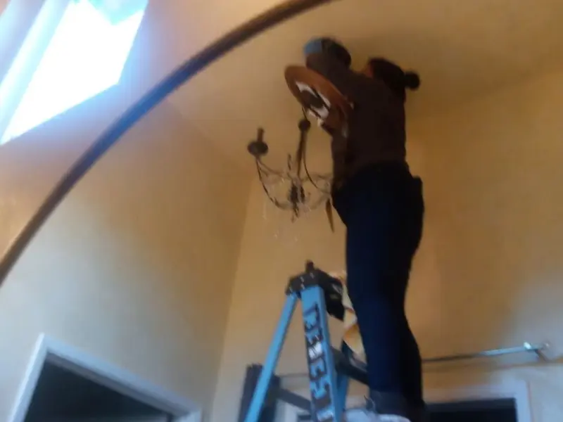 Electrician installing a chandelier in a Dalton residence
